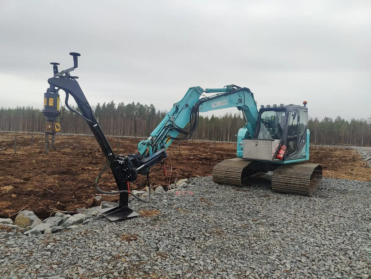 Excavator with extension boom installing screw piles