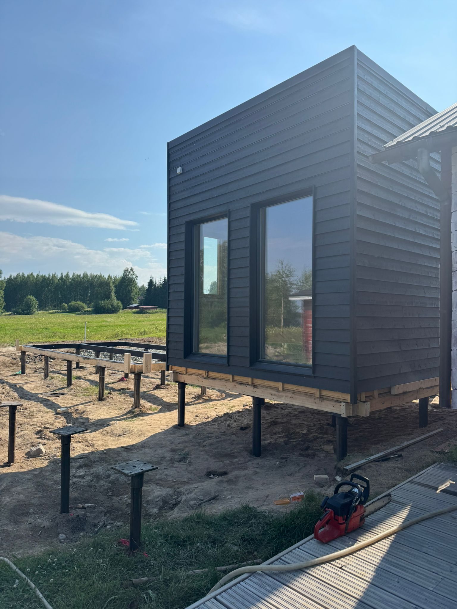 Steel screw pile foundation supporting a wooden building frame