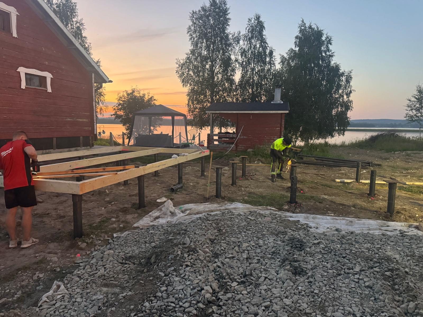 Workers building timber frame on screw pile foundations at lakeside